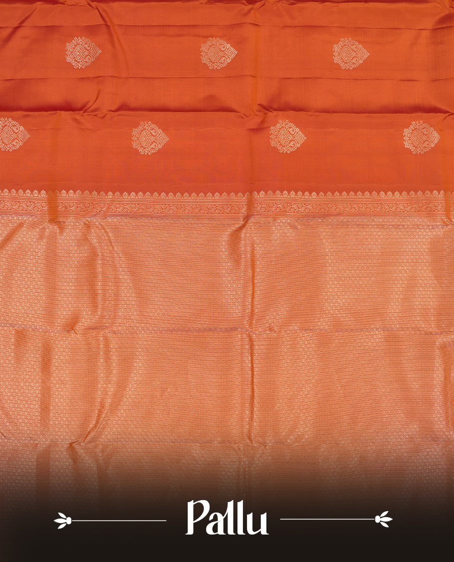 Burnt orange colour Vasundhara silk saree adorned with all-over gold motifs on the body, complemented by a self colour with gold tarditional border and paired with a matching blouse piece.