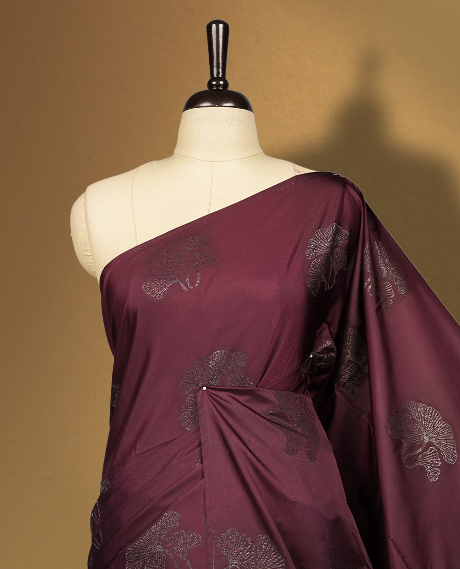 Deep brown colour semi soft silk saree, adorned with subtle floral woven motifs on the body & The design is elevated with an elegant zari border and pallu, paired with a matching blouse.