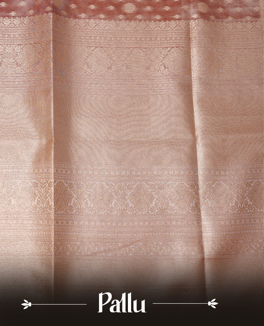 Pastel peach colour semi tissue silk saree featuring floral zari motifs on body, complemented by gold zari traditional border, paired with matching blouse piece.