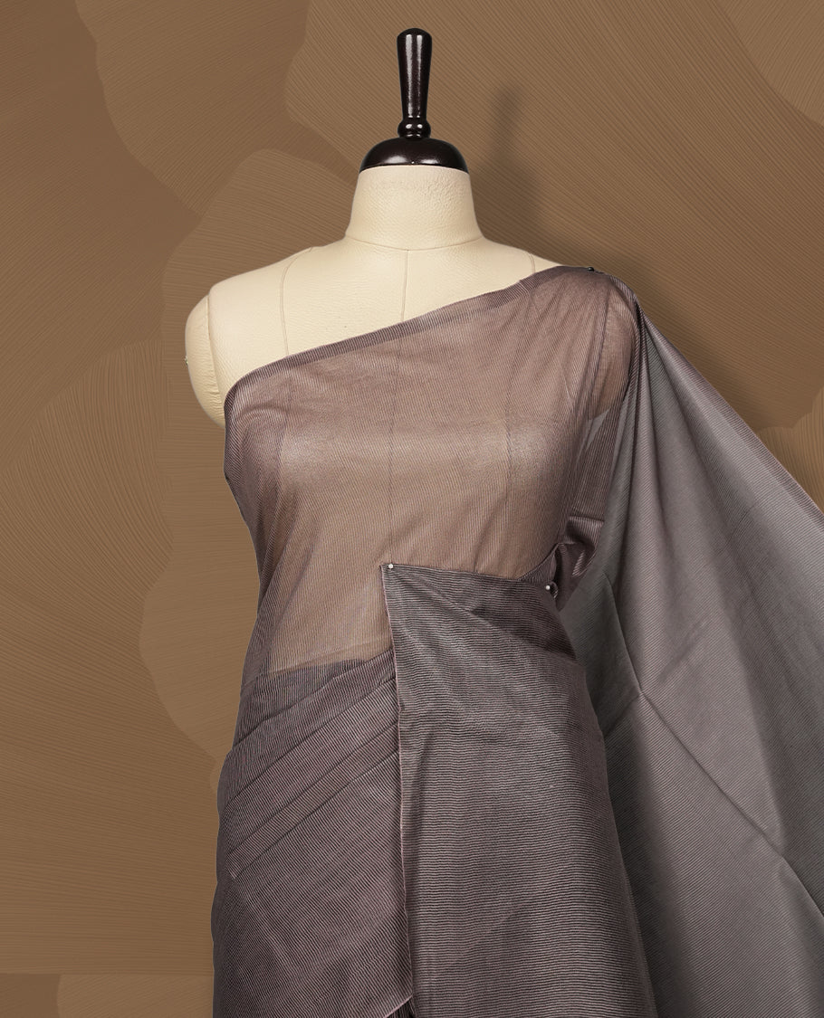 Grey brown colour semi jute saree featuring fine striped body work for a subtle texture, Accented with a geometric woven purple shaded pallu, sleek border, soft drape, and a matching blouse piece for a complete look.