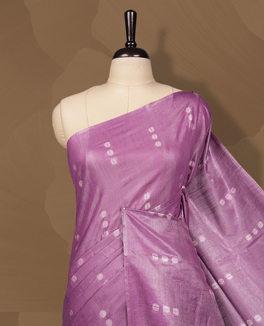 Lavender colour semi jute saree adorned with delicate woven motifs and a subtle sheen, The tassel detailed pallu enhances its charm & Paired with a matching blouse piece for an elegant finish.