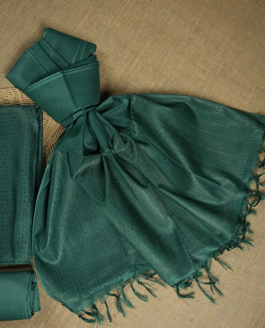 Dark aqua green colour tussar suit material featuring a subtle self copper zari woven small motifs and vertical and stripped pattern on the body, paired with a lightweight matching dupatta with tassel edges and a plain bottom piece.