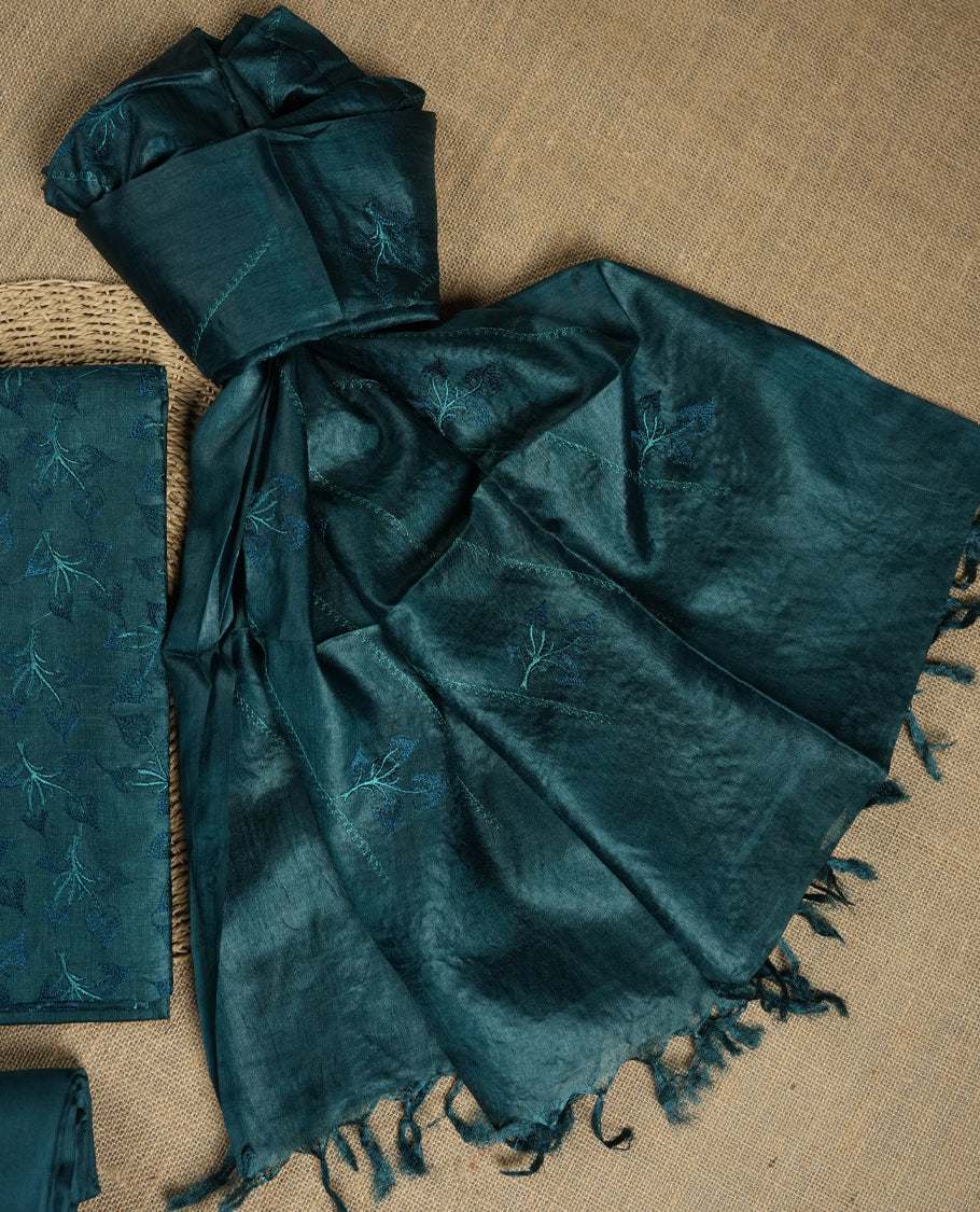Crystal teal colour tussar suit material featuring elegant floral thread embroidery on the body, paired with a soft dupatta adorned with matching embroidered motifs and tassel edges, along with a plain bottom piece.