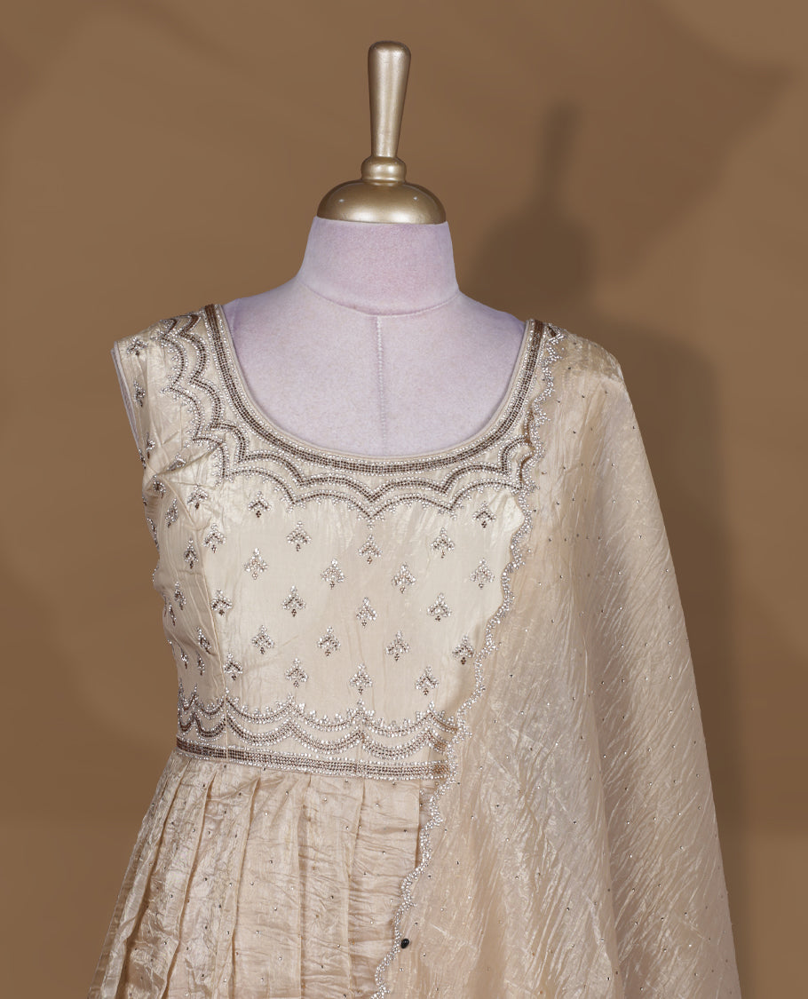 Champagne beige colour stitched gown set with sleeveless embroidered yoke, flared ankle‑length silhouette, and attached dupatta featuring delicate butti work and scalloped beaded edging.