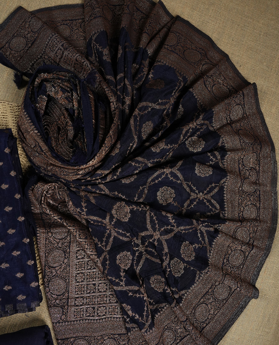 Navy blue suit material adorned with intricate light copper toned zari motifs weaving, exuding timeless elegance & Paired with a beautifully woven dupatta featuring floral and motifs and a matching plain bottom.