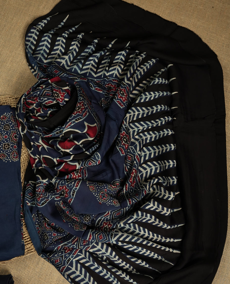 Navy blue suit material featuring intricate Ajrak inspired prints in maroon, blue, and off white & Includes a beautifully patterned dupatta and matching plain bottom.