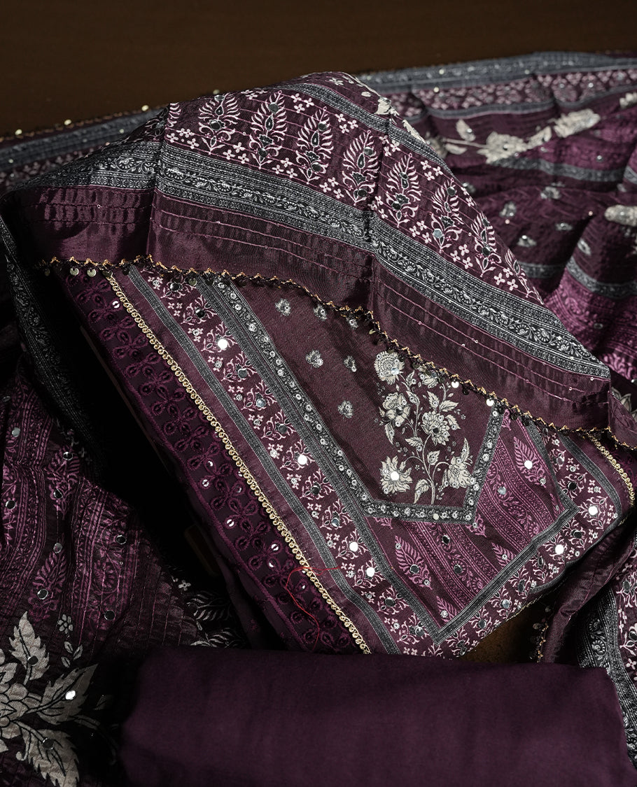 Dark purple colour churidhar material featuring Mirror and thread embroidery, foral print pattern on the self colour front panel, floral digital printed dupatta with elegant border, and matching plain bottom