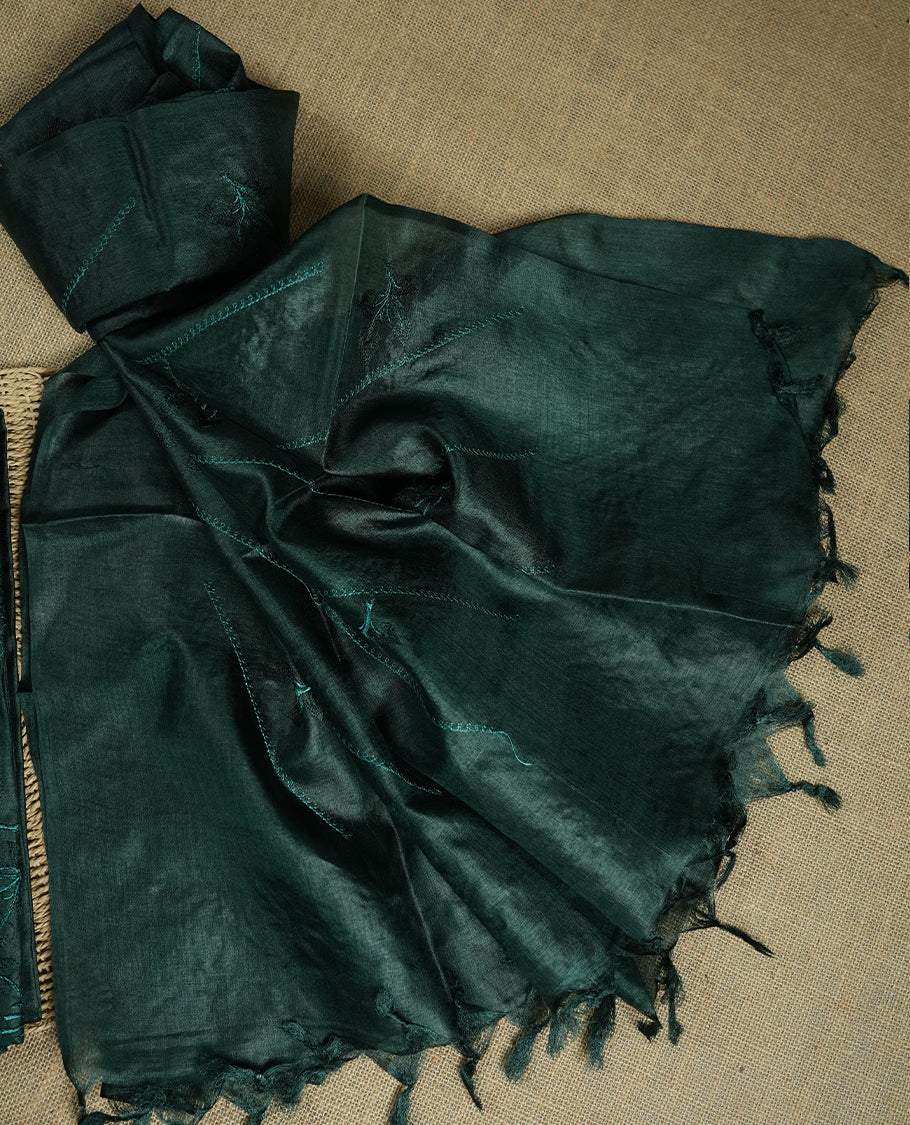 Deep jungle green colour tussar suit material featuring elegant floral thread embroidery on the body, paired with a soft dupatta adorned with matching embroidered motifs and tassel edges, along with a plain bottom piece.