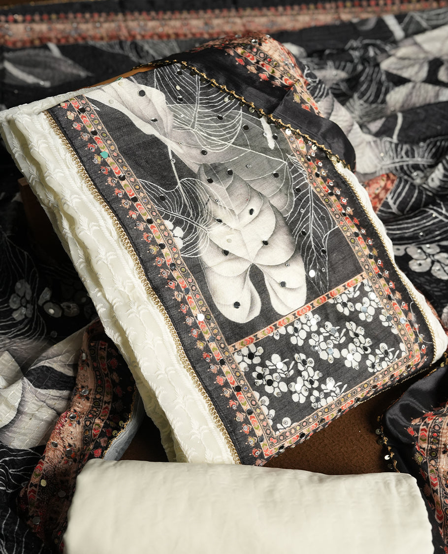Off white colour churidhar material featuring Mirror and thread embroidery, foral print pattern on the contrast black colour front panel, floral digital printed dupatta with elegant border, and matching plain bottom
