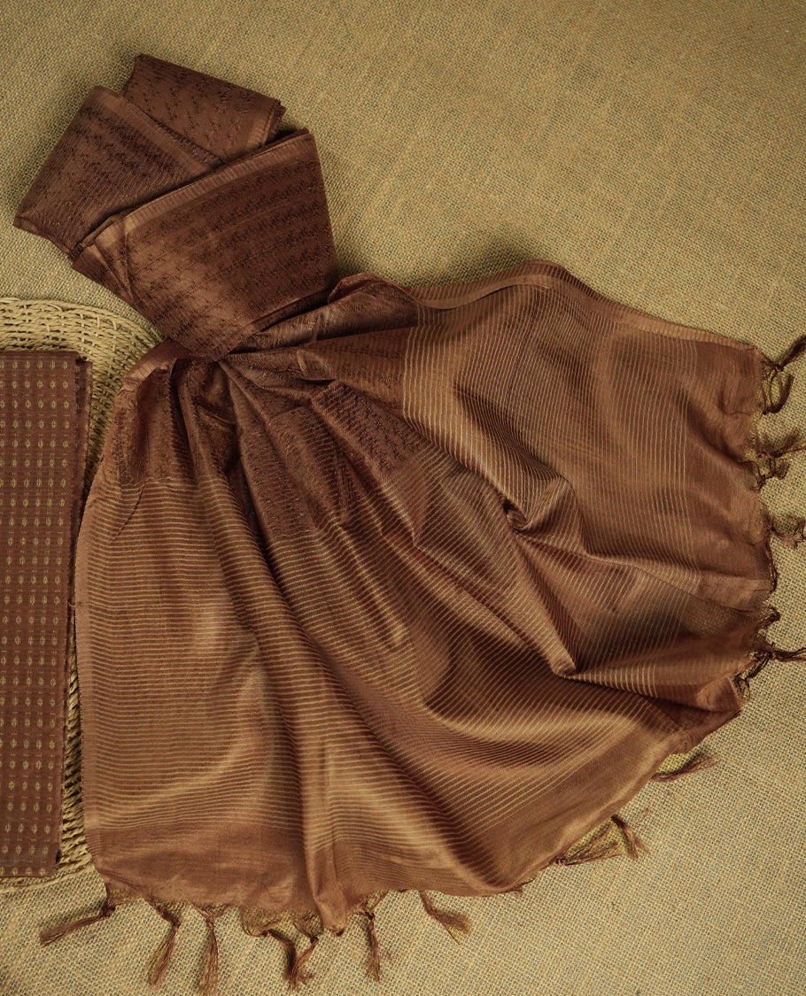 Pastel brown colour tussar suit material adorned with intricate woven patterns and subtle motifs, exuding ethnic elegance & Paired with a beautifully bordered dupatta and a matching plain bottom.