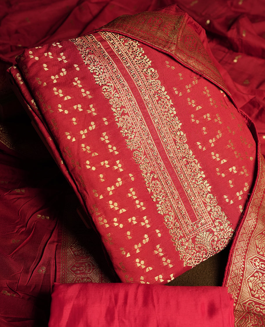 Deep maroon colour churidar material adorned with small golden stone work on the neckline, featuring intricate zari floral motifs on the body, rich zari woven border and dupatta, paired with matching plain bottom.