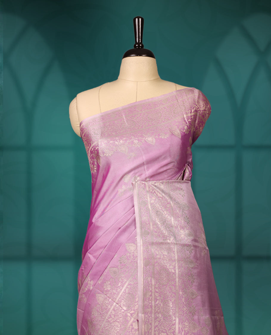 Lavender colour semi silk saree featuring delicate golden zari floral motifs across the body, complemented by a rich self-colour woven border and pallu, paired with a matching blouse.
