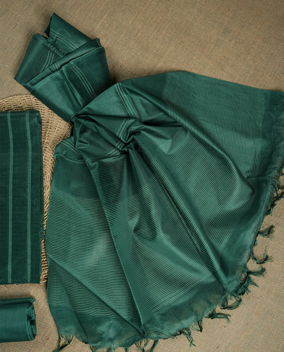 Dark Turquoise green colour tussar suit material featuring a subtle self woven pattern and vertical lines on the body, paired with a lightweight matching dupatta with tassel edges and a plain bottom piece.