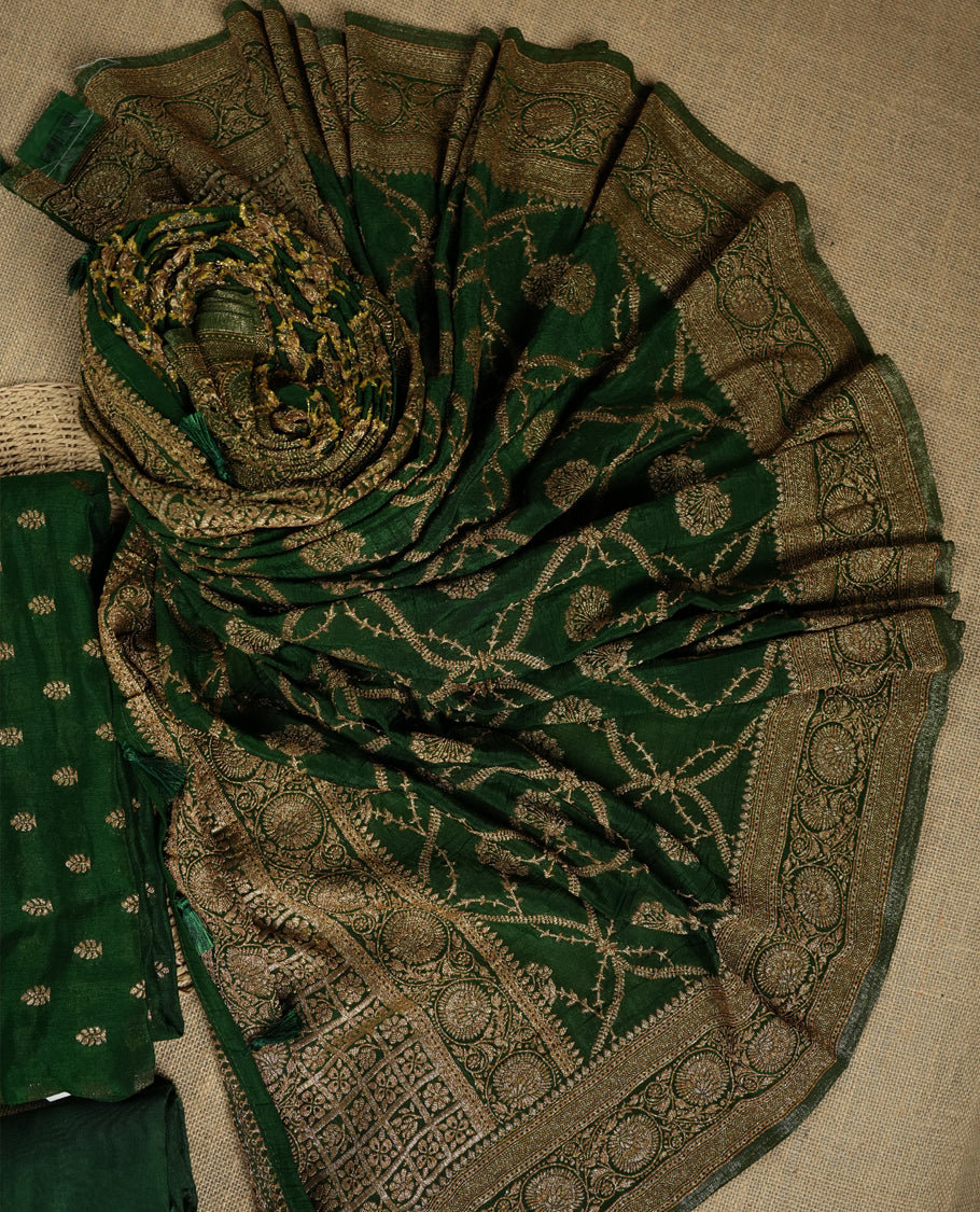 Royal Green suit material adorned with intricate golden toned zari motifs weaving, exuding timeless elegance & Paired with a beautifully woven dupatta featuring floral and motifs and a matching plain bottom.