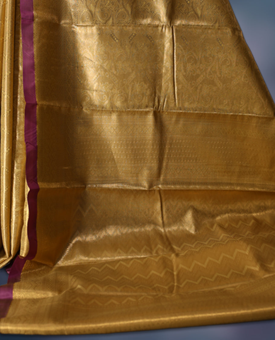 Golden semi silk brocade saree with intricate self brocade work across the body, paired with a rich contrast violet border and matching pallu. Includes a coordinating blouse for an elegant traditional look.