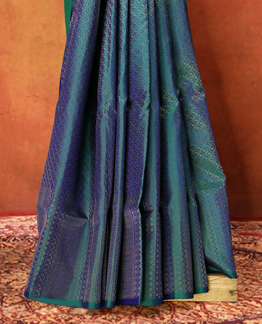 Peacock blue and green dual tone pure Mayuri silk saree featuring intricate gold Zari woven patterns across the body, highlighted with a rich geometric woven border, with matching blouse