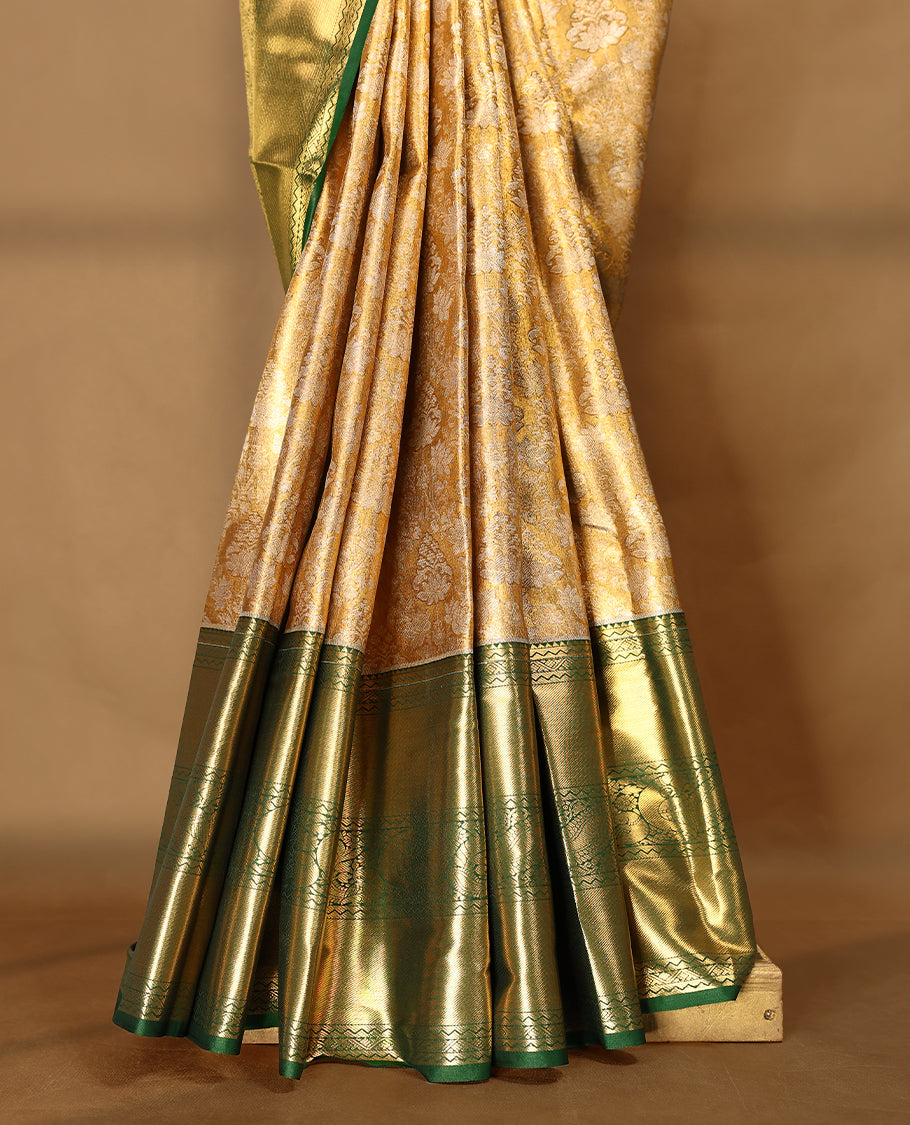 Gold colour tissue brocade saree with gold and silver zari lotus pattern on body, gold zari peacock and flower traditional green border, rich matching pallu with Antique zari motifs, paired with matching blouse.