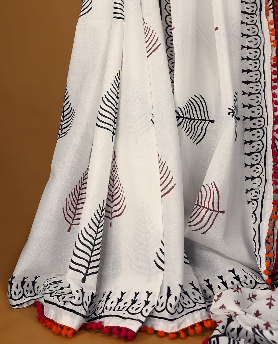 White cotton saree with black handblock prints, a detailed border enhanced with a combination of pink and orange piping, and with contrast blouse.