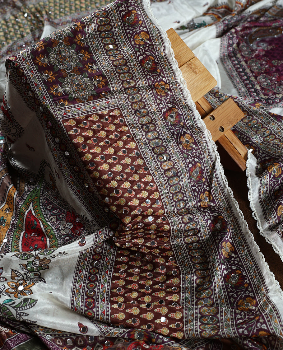Off white colour churidhar material beautifully detailed with grape colour traditional paisley and floral prints, mirror work highlights, paired with a plain white bottom and a matching printed dupatta with lace border.