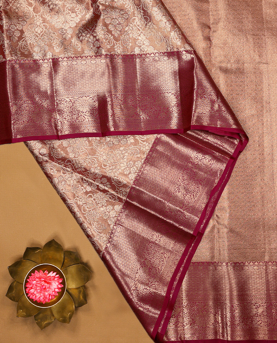 Pastel maroon Colour Kancheepuram tissue silk saree adorned with intricate silver floral zari work on the body, beautifully highlighted by a maroon traditional Rudraksham and floral design border, and paired with a matching blouse.