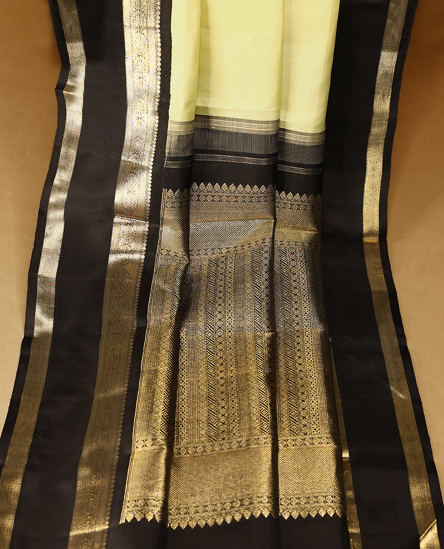 Key lime Colour pure traditional Kanchipuram silk saree adorned with intricately woven antique zari Chakkram motifs on the body, complemented by a Contrast black traditional border featuring Chakkram designs, and paired with a matching blouse.