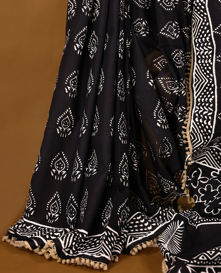 Black cotton saree features intricate white handblock prints, a beautifully detailed border with Beige piping and Self Coloured Blouse