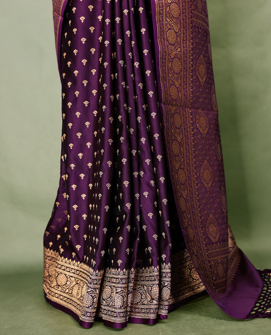 Grape wine colour semi Banaras satin crepe saree featuring gold zari woven small motifs across the body, complemented by an intricately designed traditional banarasi border and richly woven pallu, paired with a matching blouse piece.