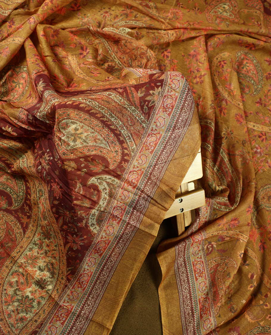 Dark ochre yellow colour churidhar material featuring intricate paisley prints and delicate embroidery with stone highlights, paired with a plain matching bottom and a printed dupatta.