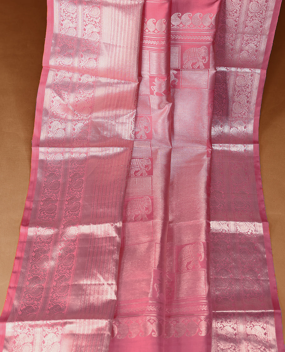 Light rose pink Colour traditional Kancheepuram silk saree adorned with antique zari small peacock motifs on the body, featuring a traditional border with light silver zari peacock and floral patterns, and paired with a matching blouse.