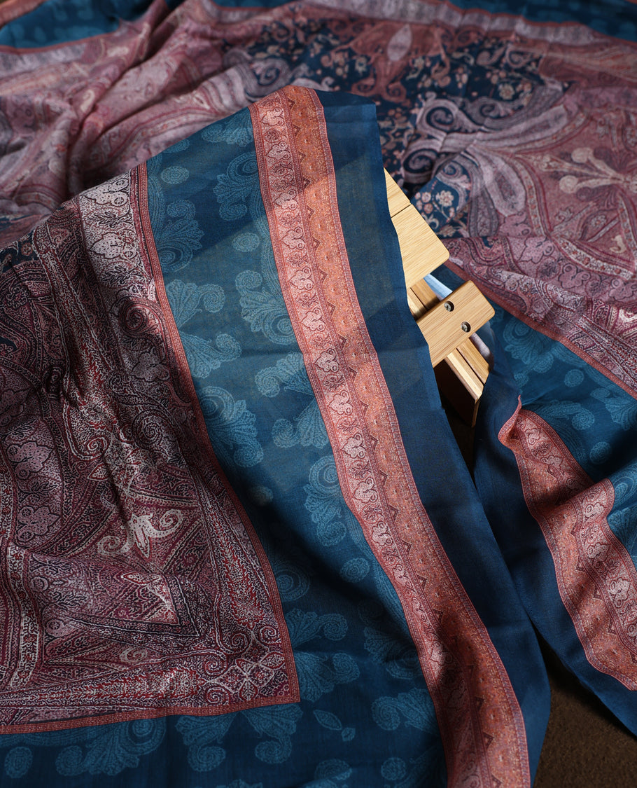 Dark peacock blue colour churidhar material with subtle paisley motifs, sequin highlights, and woven border design, paired with a plain matching bottom and a soft printed dupatta for a graceful ethnic look.