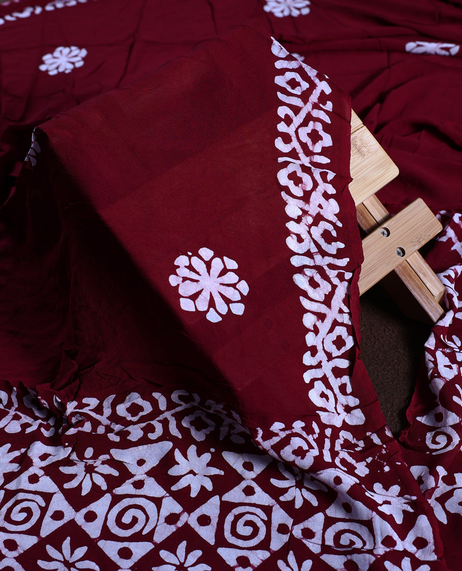 Red wine colour churidhar material adorned with gold and copper toned floral patterns and bold block designs, paired with a plain matching bottom and stylish dupatta, perfect for festive evenings and traditional gatherings.