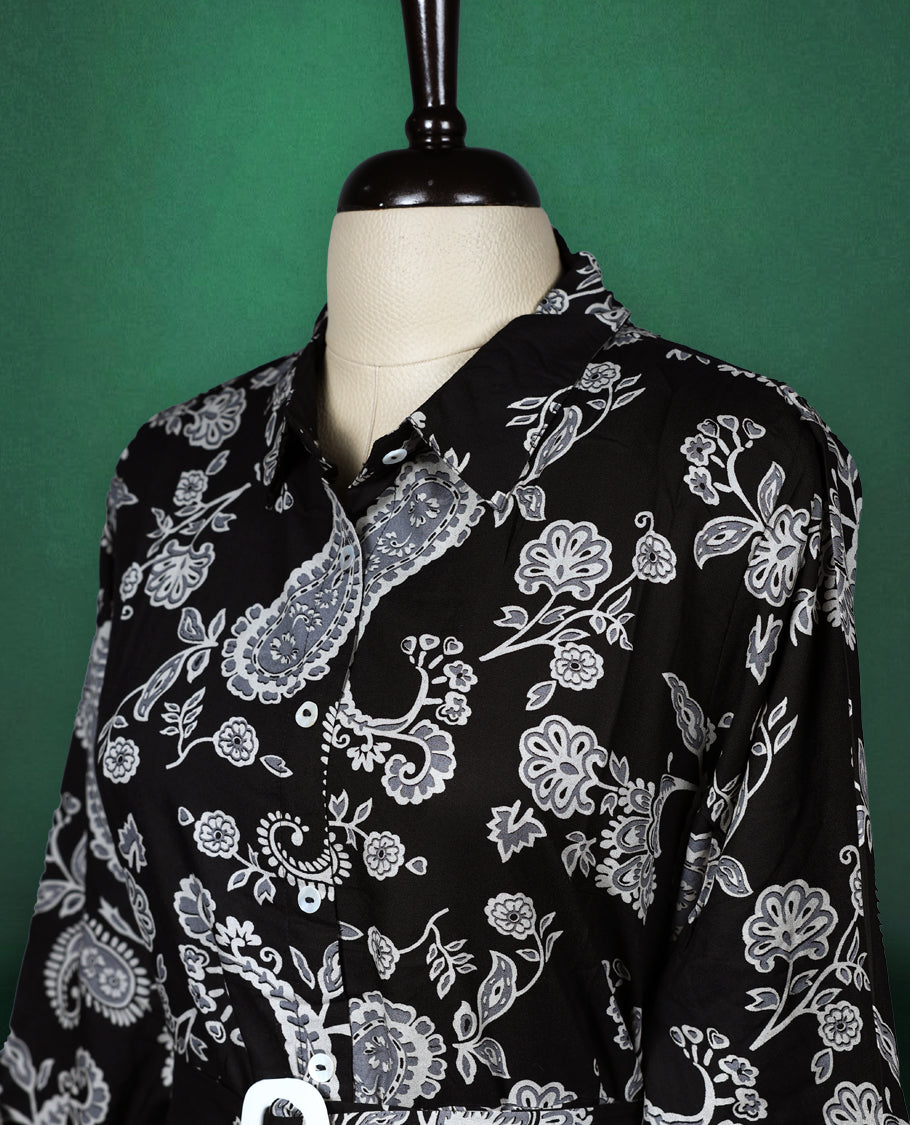 Black shirt style kurti dress featuring elegant white paisley prints, designed with a collared neckline, front buttons, 3/4th sleeves, and a matching fabric belt to accentuate the waist perfect for a smart Indo western look.