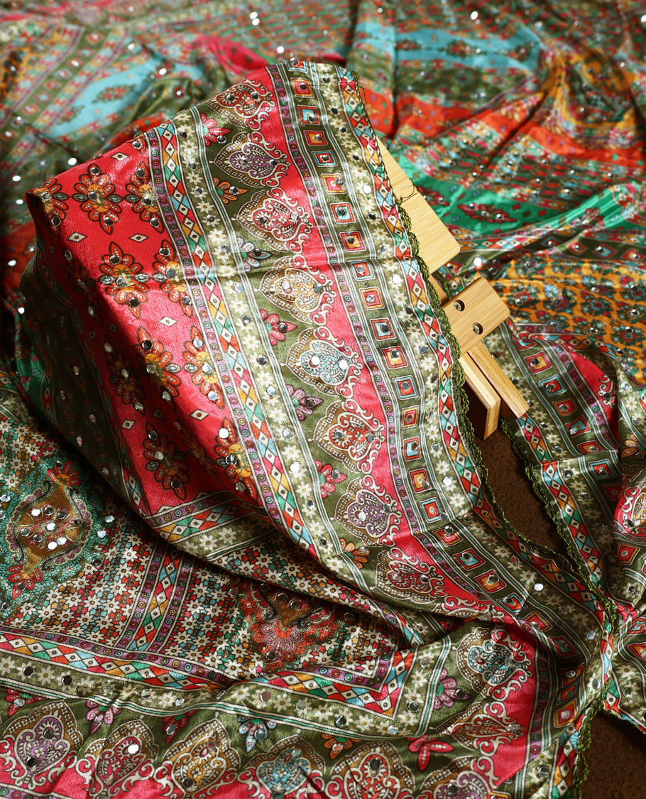 Elegant olive green churidhar material with vibrant multicolour geometric and paisley prints, enhanced with delicate mirror work, paired with a plain matching bottom and bold printed dupatta, perfect for festive occasions.