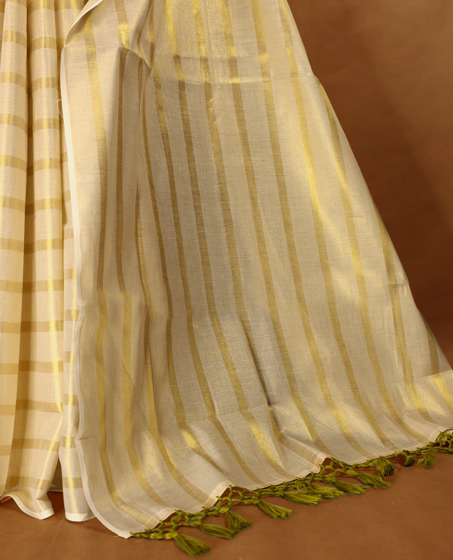 Light Gold colour Tissue Kerala saree featuring Gold zari Striped body, with Olive Green colour tassels with a matching blouse perfect for festive occasions.