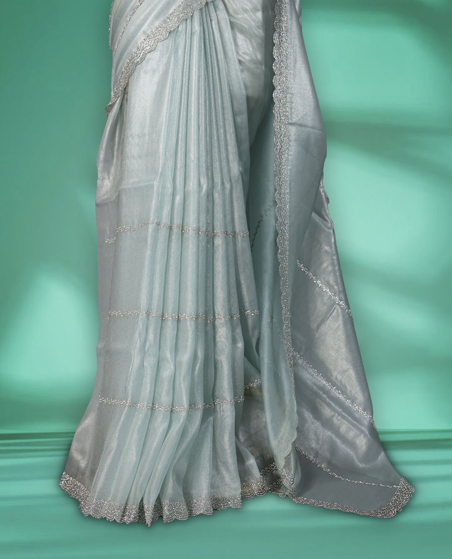Icy blue colour net shimmer fancy saree adorned with subtle horizontal White stone patterns on the body, paired with a delicate stone worked border, with matching blouse