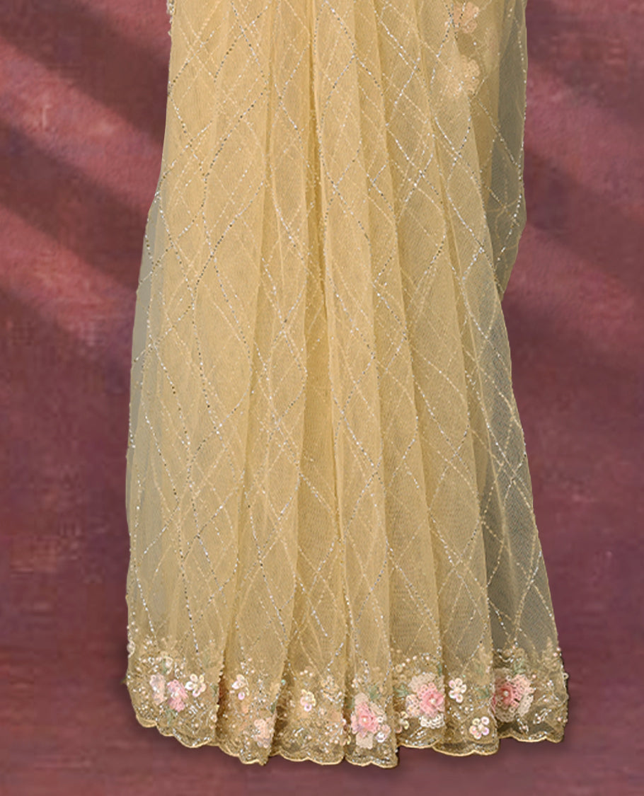 Pastel yellow colour net designer saree featuring crisscross cut beads detailing on the body, adorned with beads and sequin worked floral kodi scallop border, paired with a matching worked blouse