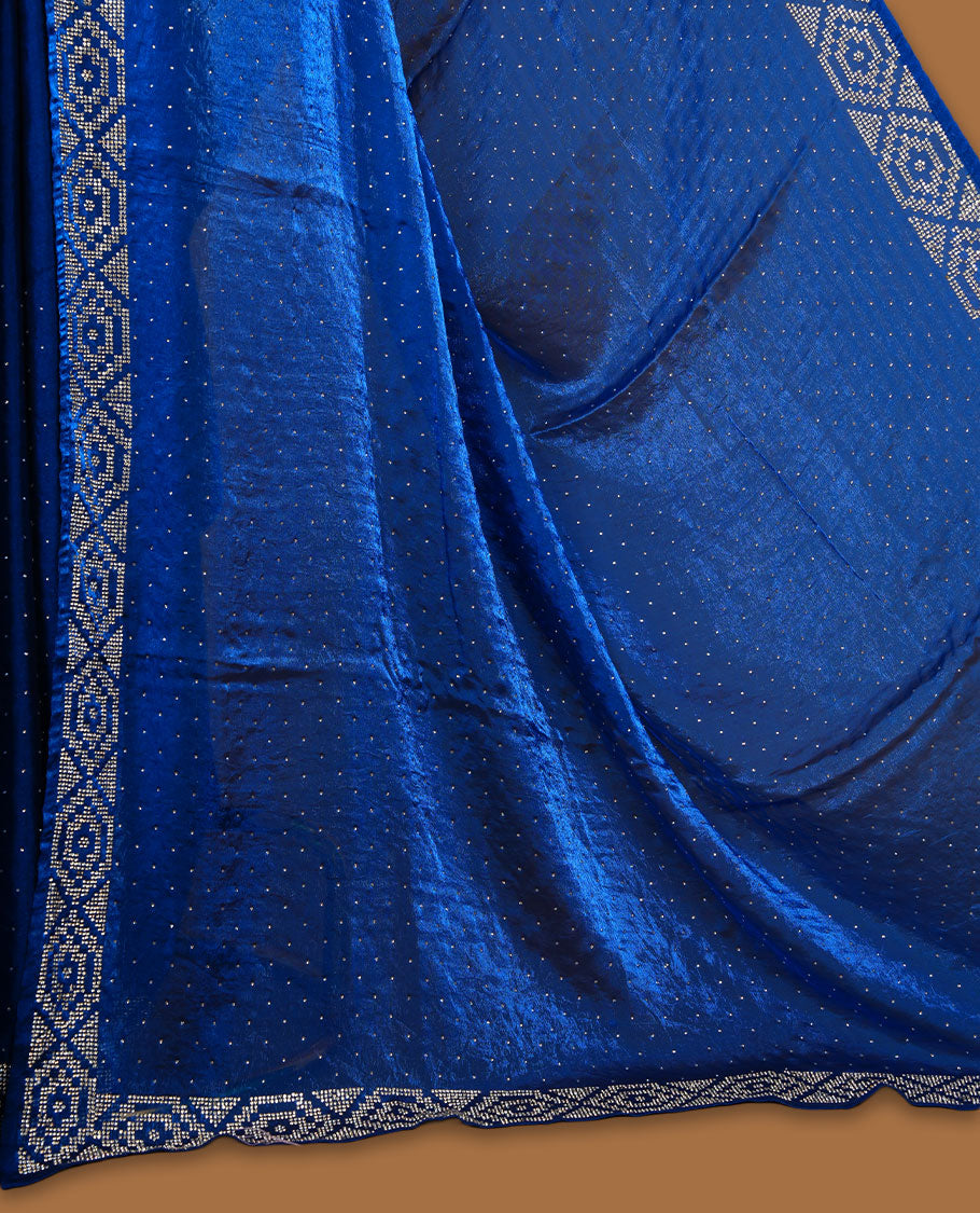 Royal Blue colour chiffon designer saree, featuring delicate scattered stone detailing all over the body, highlighted with intricate stone work and a heavy geometric stone pattern along the border and pallu, paired with a matching embellished blouse.a