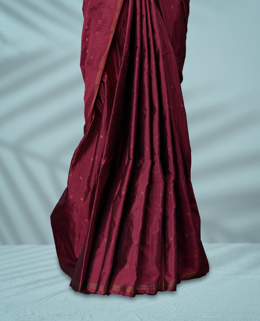 Maroon Red colour semi silk saree features a subtle checked body design with small woven motifs, a simple gold zari border, and comes with a matching blouse.