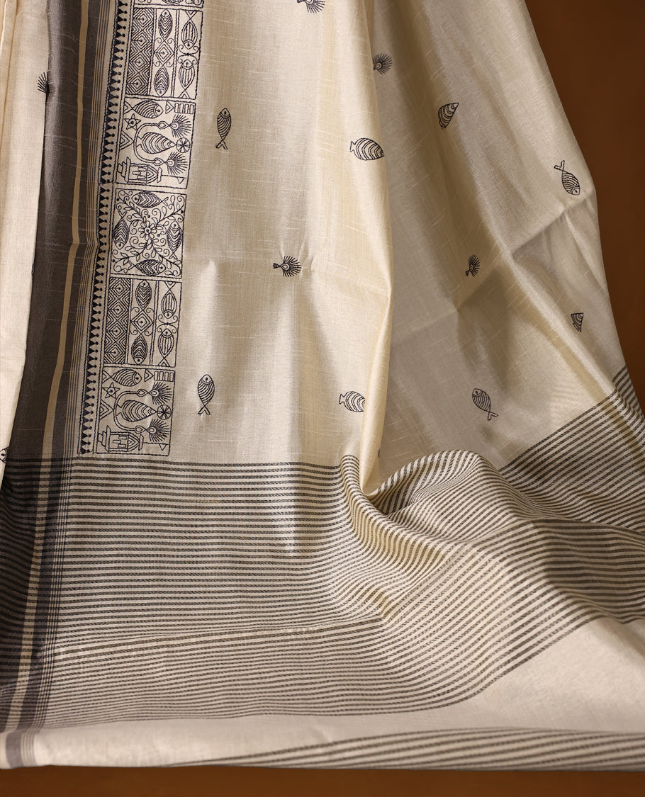 Cream colour Soft Tussar saree adorned with intricate grey woven buttas across the body, complemented by an ornate grey border featuring traditional motifs, and finished with a striped pallu, paired with a matching blouse.