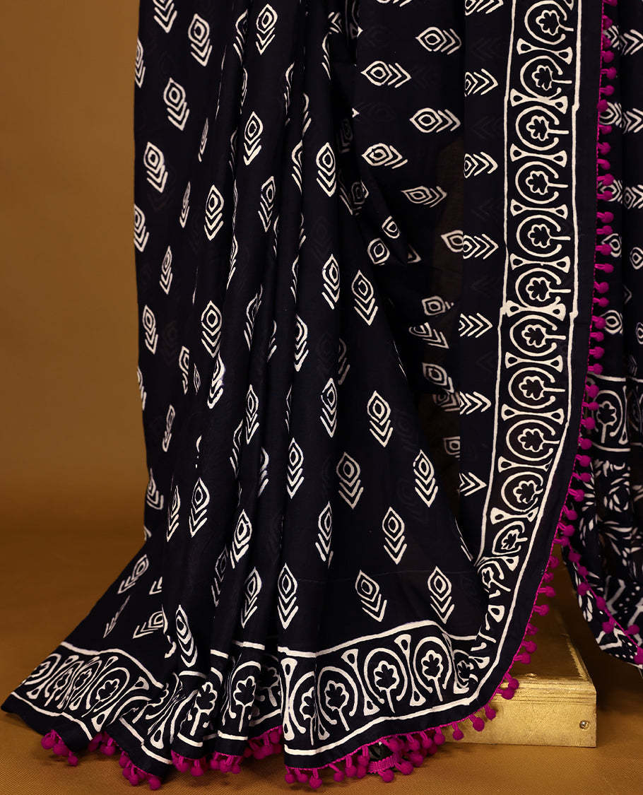 Black cotton saree features intricate white handblock prints, a beautifully detailed border with Pink piping and Self Coloured Blouse