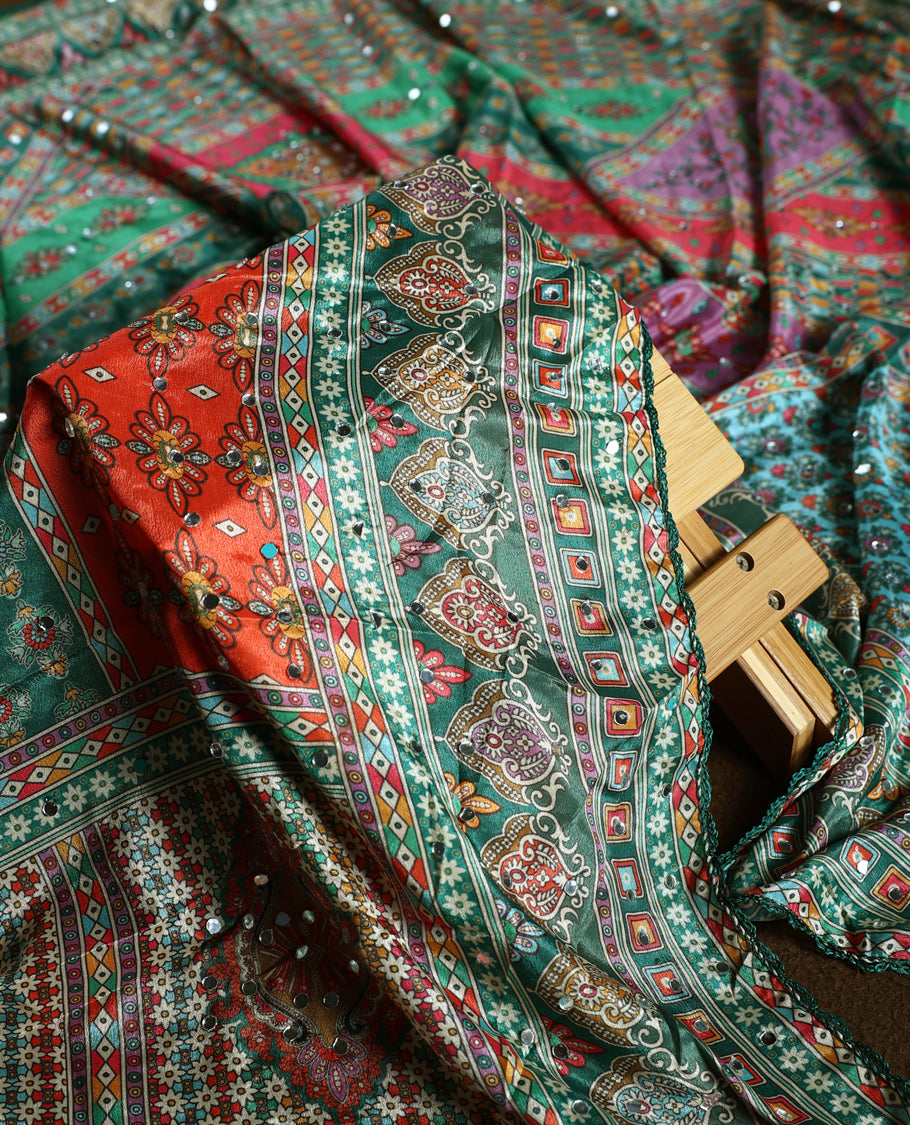 Green colour churidhar material with vibrant multicolour geometric and paisley prints, enhanced with delicate mirror work, paired with a plain matching bottom and bold printed dupatta, perfect for festive occasions.