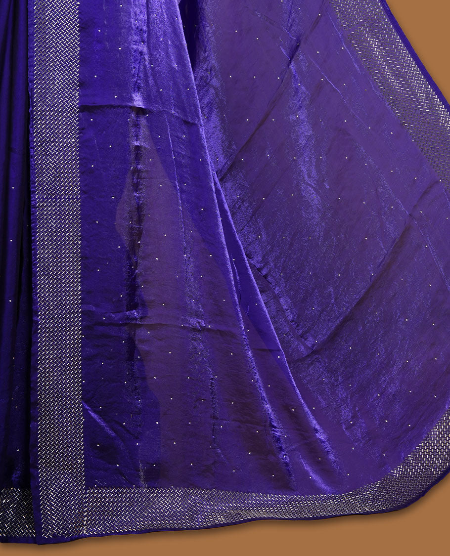Dark violet colour chiffon designer saree, featuring dainty scattered stones on the body, enriched with dense stone work and a heavy metallic stone border and pallu, paired with a matching blouse.
