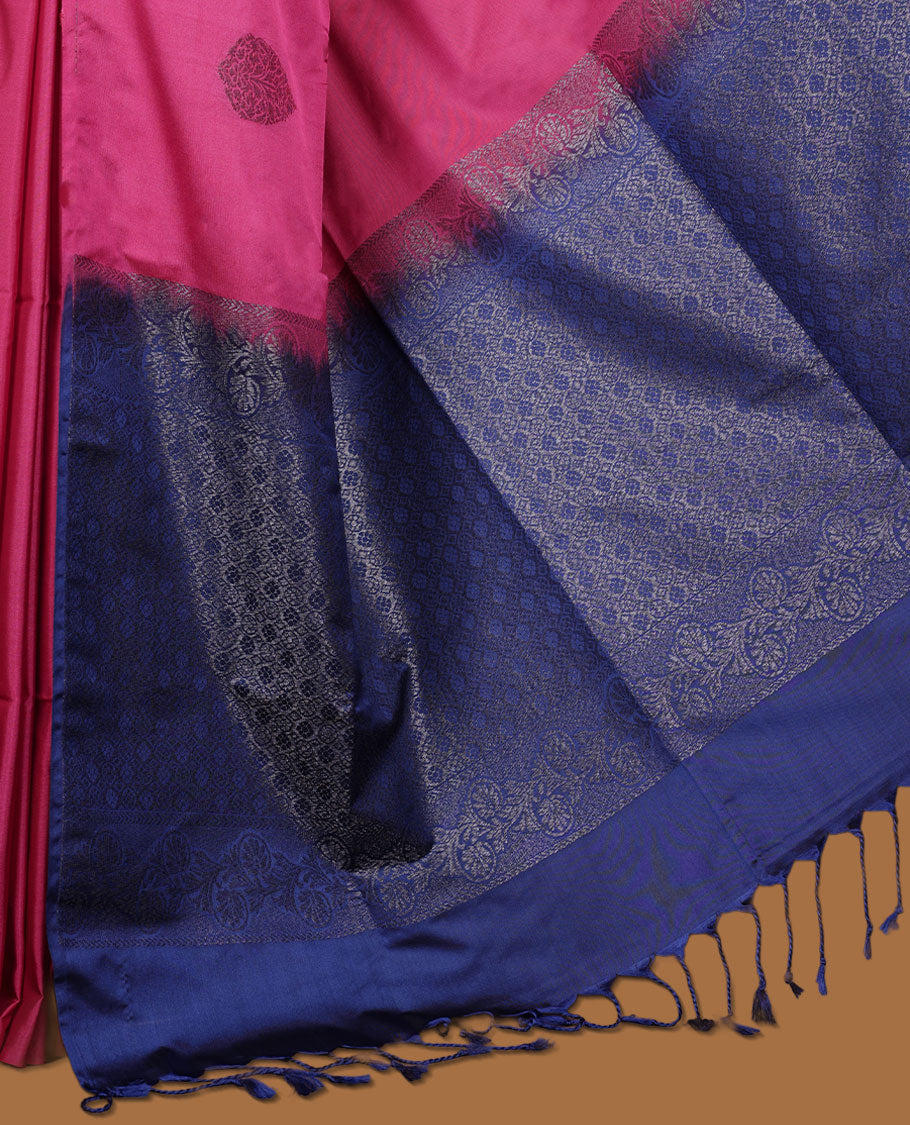 Magneta colour semi soft silk saree adorned with delicate woven floral motifs on the body, complemented by a contrast blue colour woven pallu with intricate detailing and tassel accents without border & Comes with a matching blouse piece.