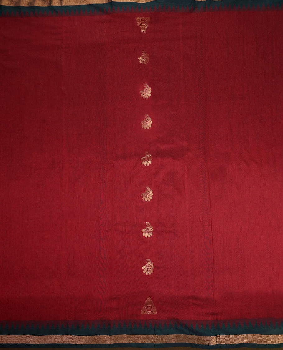 Brick red and Dark Green Kalyani cotton saree featuring delicate golden floral and peacock motifs, highlighted with an intricately woven zari border and pallu, paired with a matching blouse