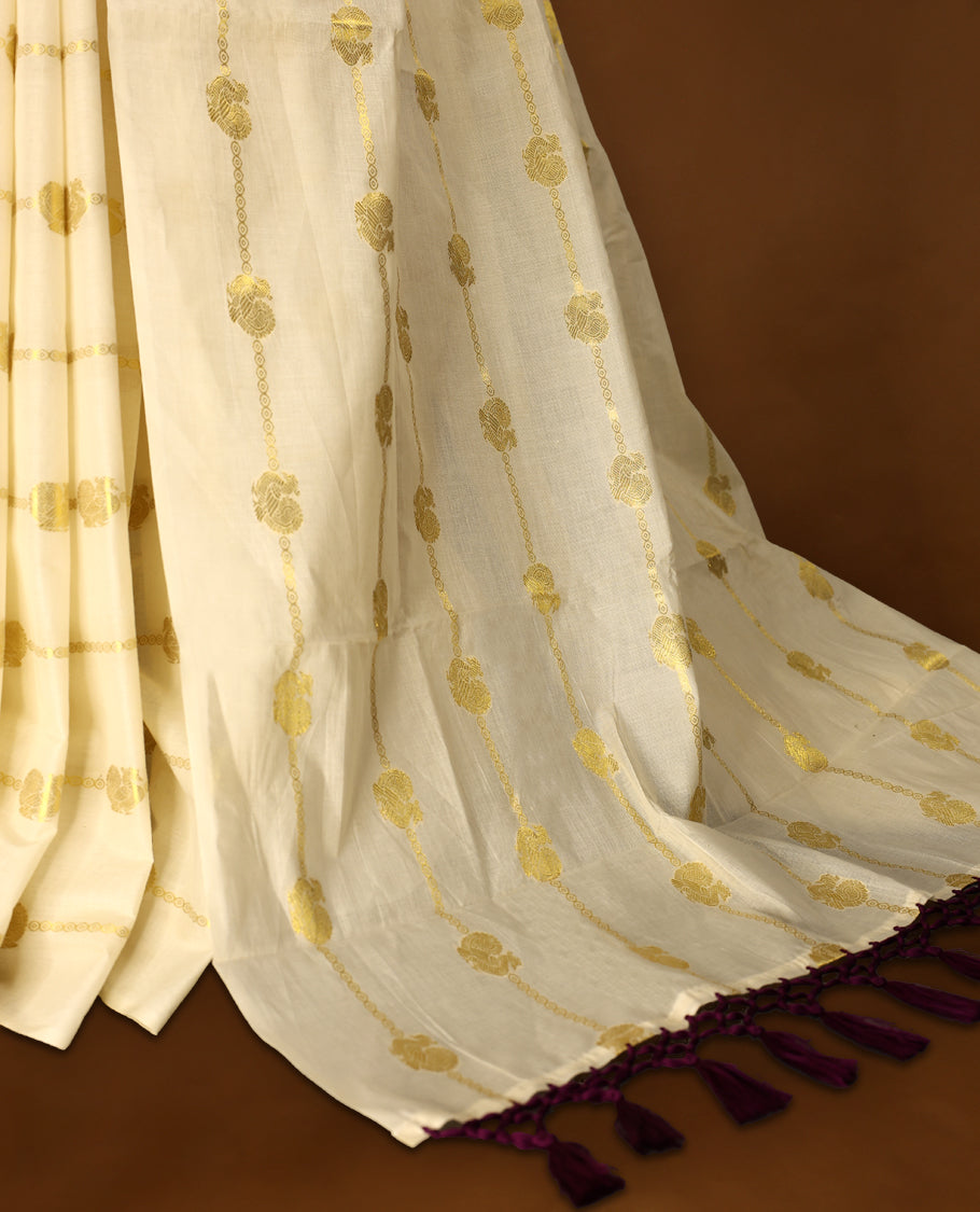 Elegant off white colour cotton Kerala saree featuring a gold Zari stripes with peacock motifs on body, with purple colour tassels offering a classic and graceful look, paired with a matching blouse.