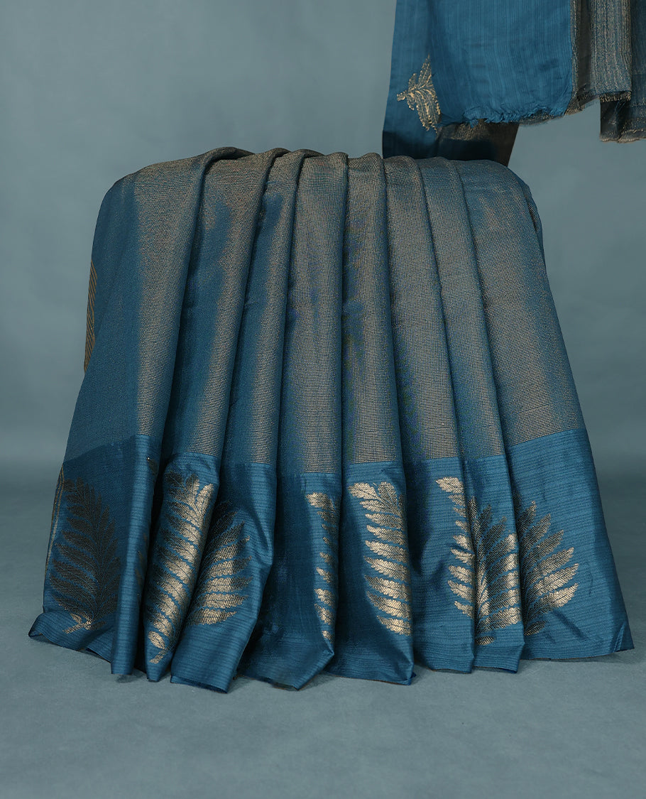 Blue Colour Semi Tussar Silk saree featuring golden zari horizontal lines across the body, adorned with bold Leaf motifs on the border, paired with a matching blouse.