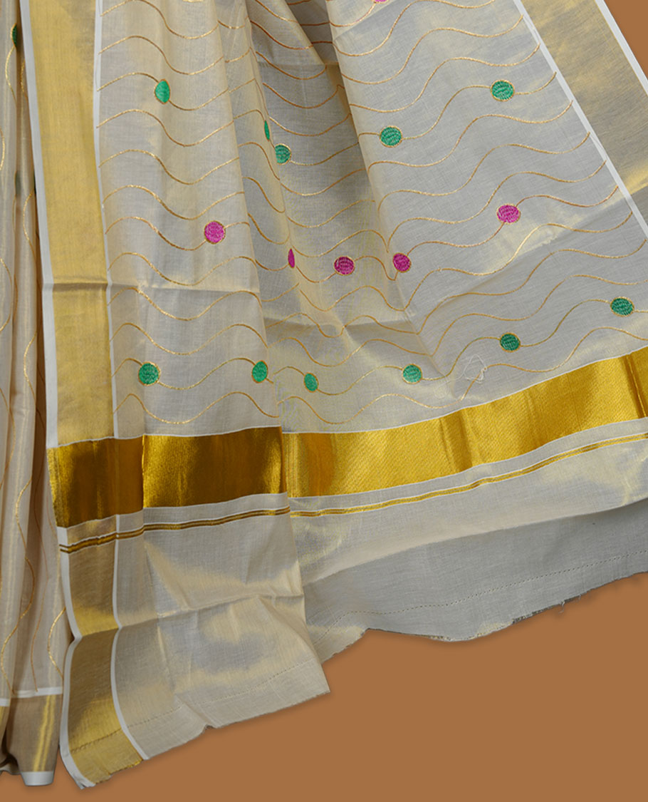 Off white colour cotton Kerala saree with wavy zari lines and colourful motifs, complemented by a classic golden zari border and matching blouse.