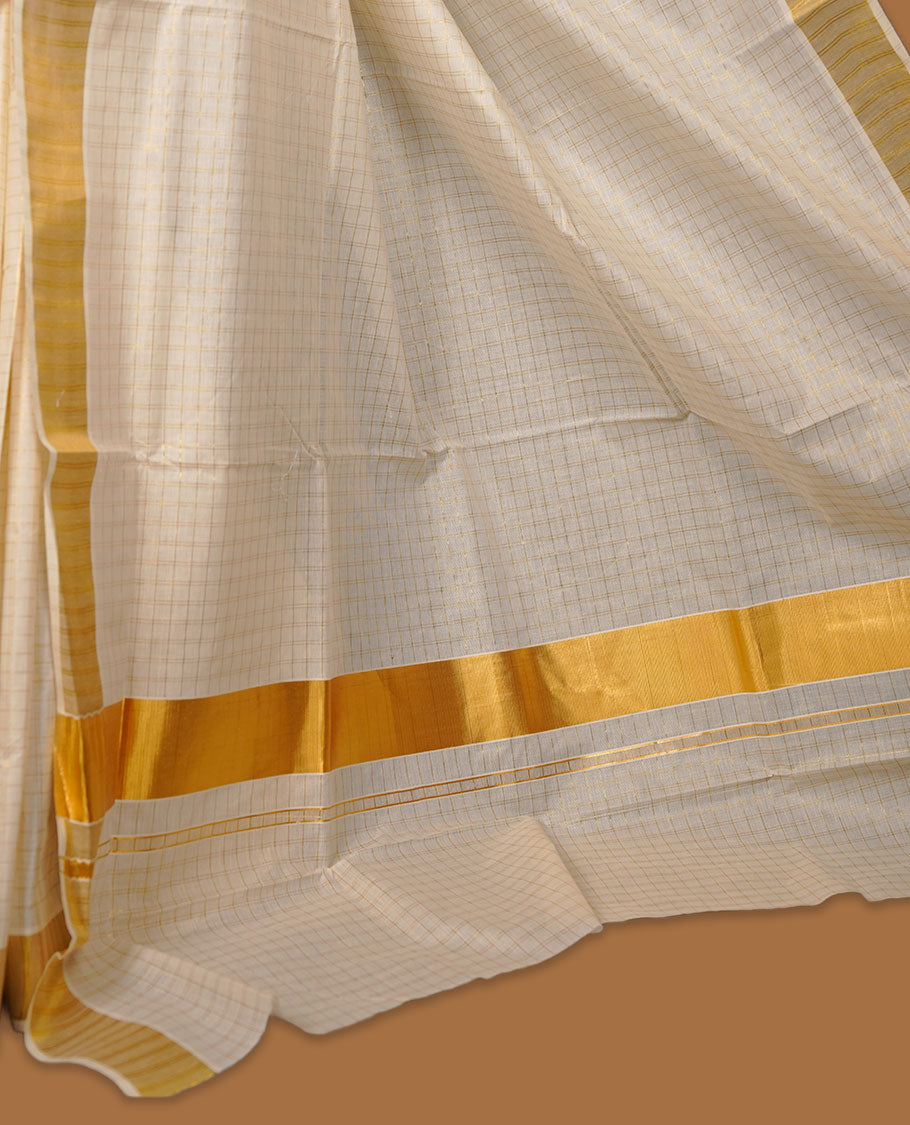 Off-white colour cotton Kerala saree featuring a subtle gold checkered weave, highlighted with a classic rich gold kasavu border along the edges and pallu, and paired with a matching blouse perfectly blending traditional charm with understated elegance.