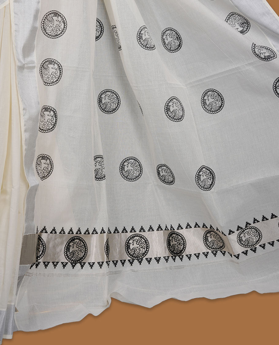Off-white colour cotton Kerala saree featuring a subtle silver kasavu border, adorned with classic black cirlcle peacock motifs across the body and pallu, and paired with a matching blouse.