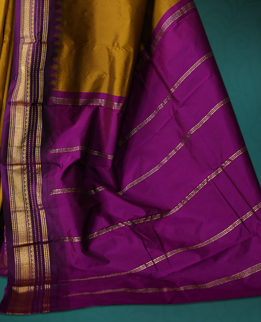 Mustard yellow semi silk saree with plain body, royal ourole pallu and matching purple border adorned with golden zari, accented with temple motifs along the edges, Paired with a matching blouse, perfect for festive occasions.